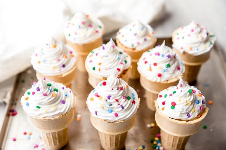 Ice cream cone cupcakes with frosting and sprinkles on a baking tray