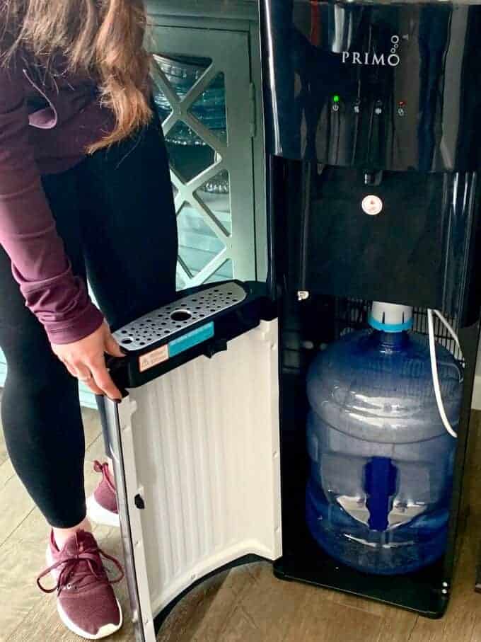 A person filling up a water cooler
