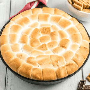 Golden toasted marshmallows arranged in a skillet for a s'mores dip.