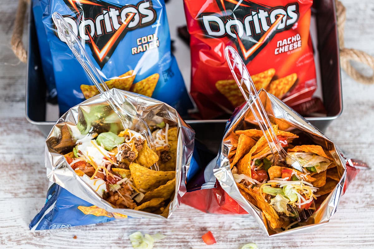 Two open bags of Doritos with taco toppings inside each bag. 