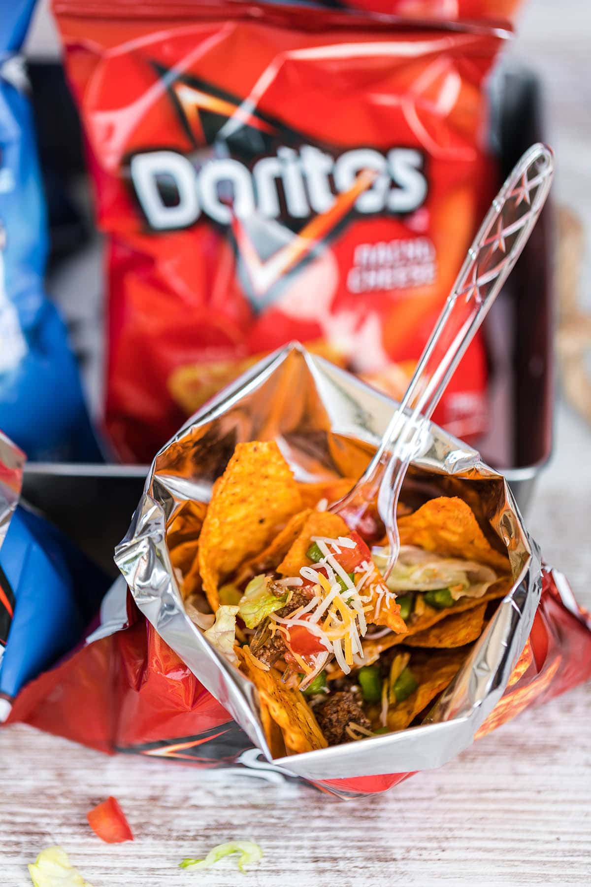 Open bag of Doritos filled with taco ingredients.