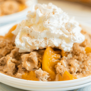 peach dump cake with whipped cream on top on a white plate