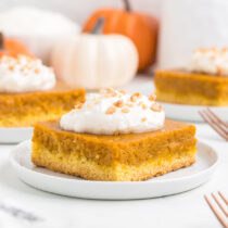 Pumpkin Gooey Butter Cake on a plate with whipped topping on top.
