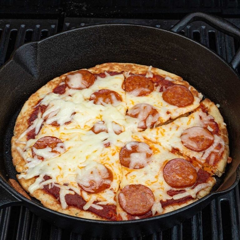 campfire pizza in a skillet on top of grill.
