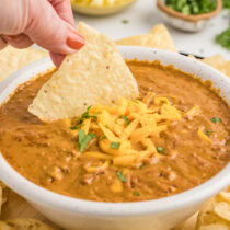 tortilla chips dipped into chili cheese dip.