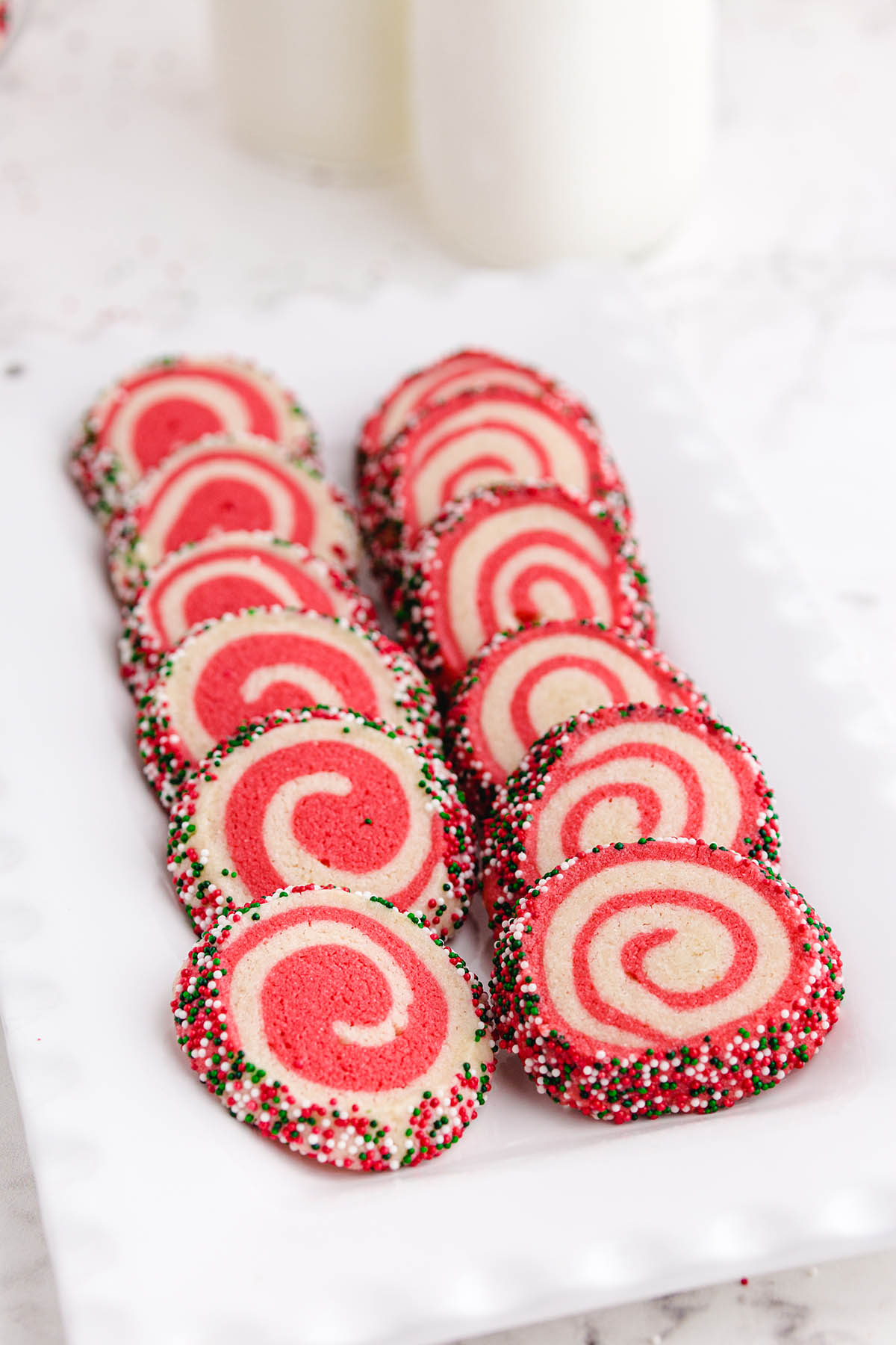 a couple of Christmas Pinwheel Cookies lined up on a white plate.