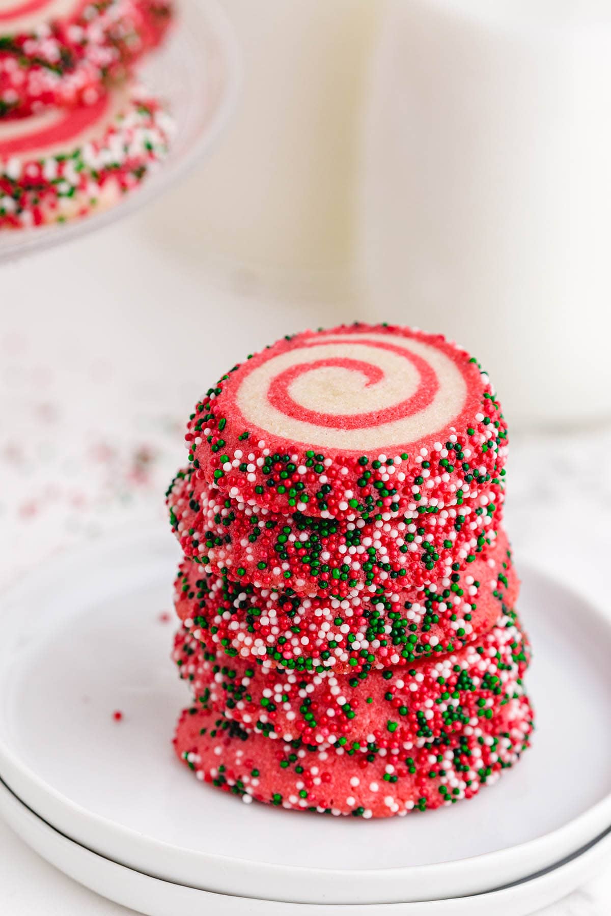 a stack of Christmas pinwheel cookies with colorful sprinkles.