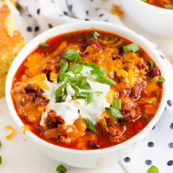 Instant Pot Chili in a white bowl with sour cream and onion