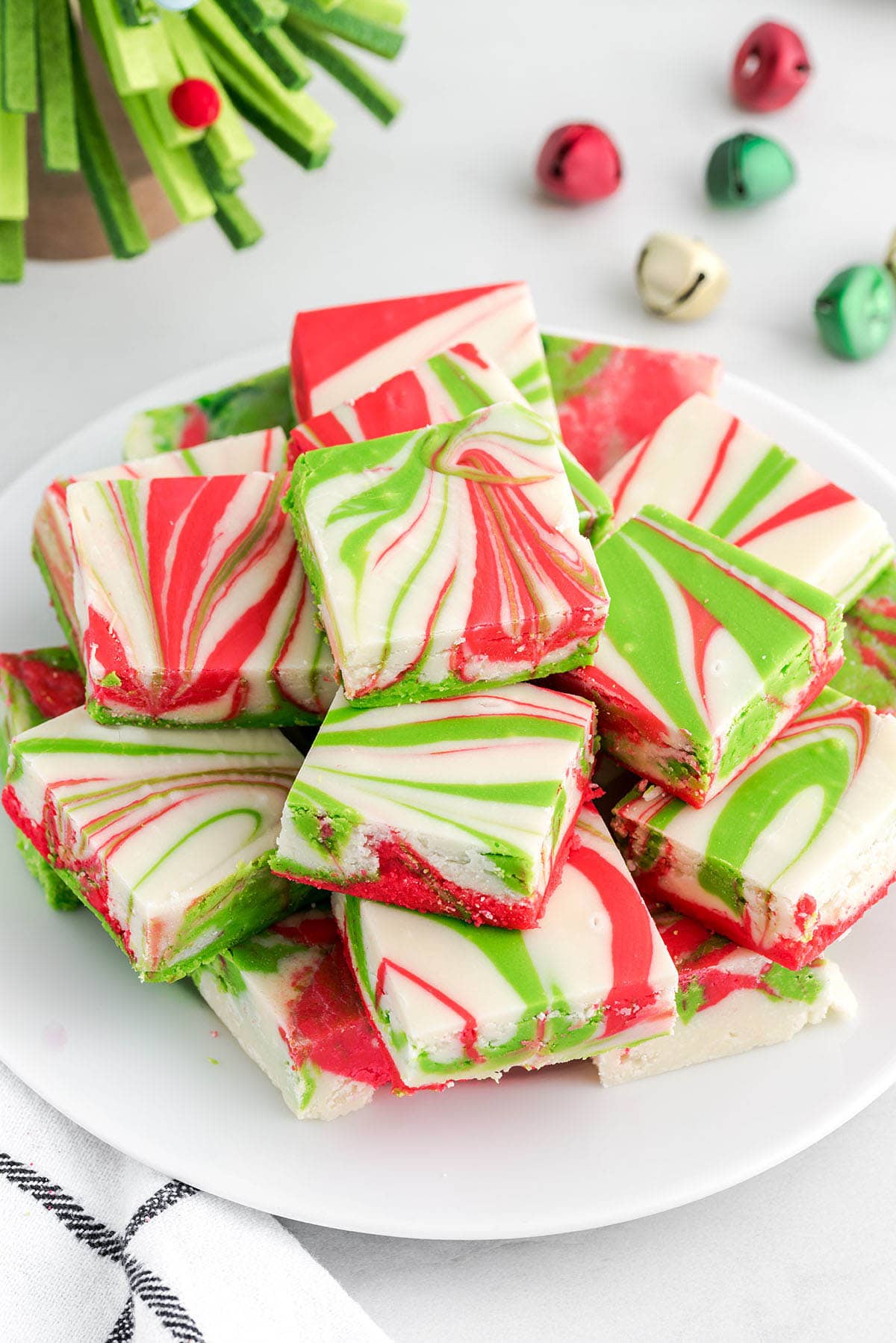 Christmas Fudge squares with red, green, and white swirled patterns stacked on a white plate.