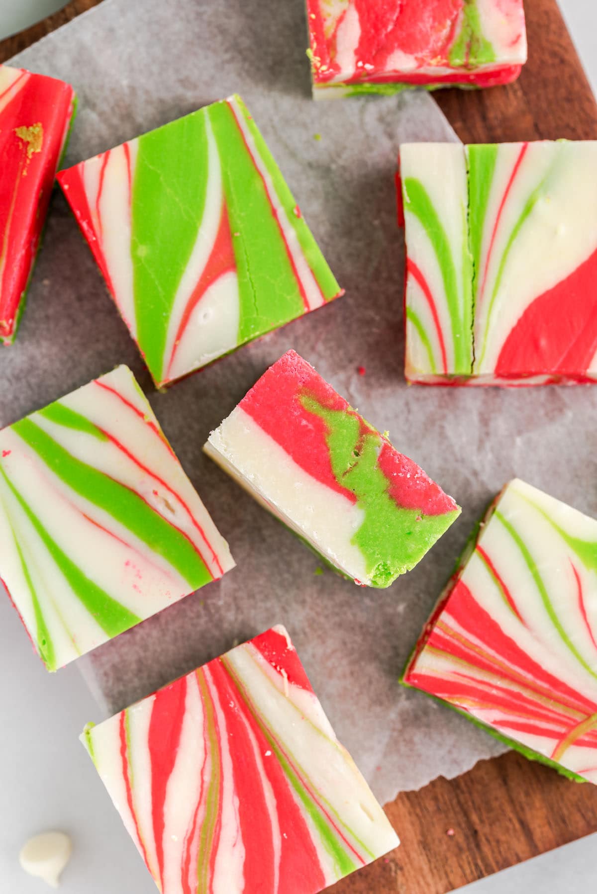 Slices of Christmas Fudge with red, green, and white swirls arranged on parchment paper.