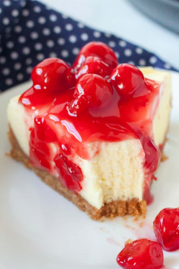 A piece of cheesecake with cherries with a bite out of it