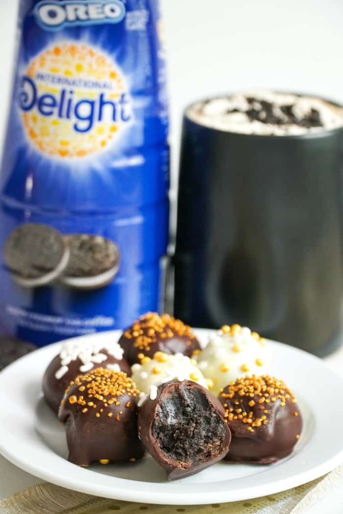 Peppermint Bark Oreo Cookie Balls on a white plate with coffee in the background