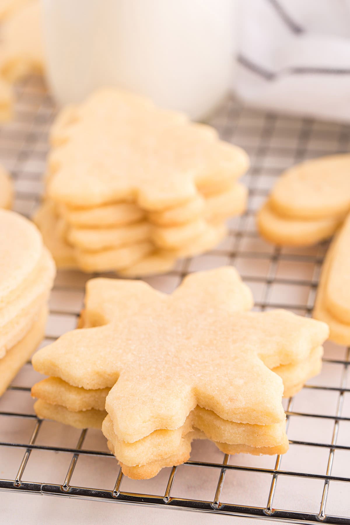 snowflake shaped cut out sugar cookies on a cooling rack.