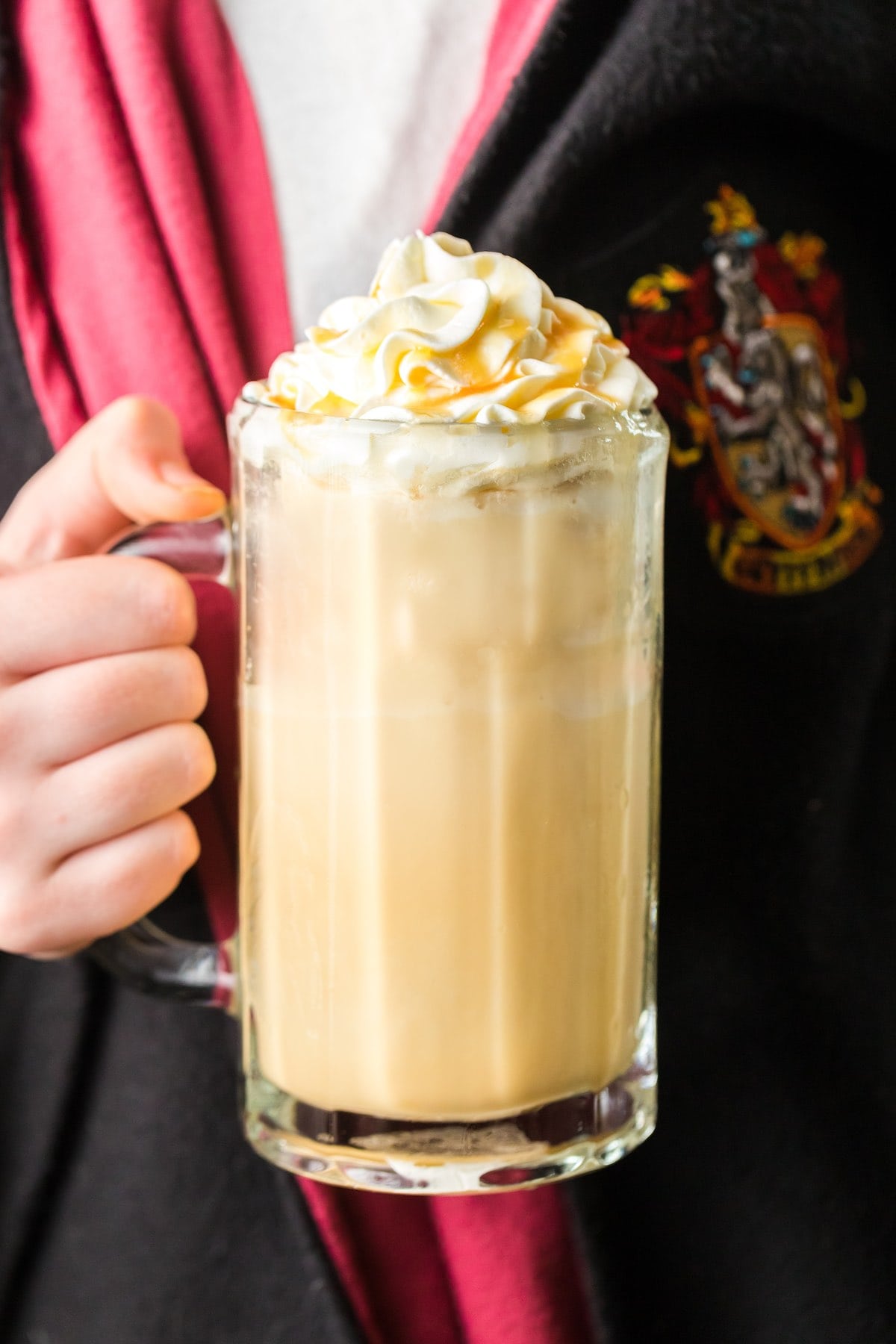 kid holding a glass of butterbeer while wearing harry potter's robe. 