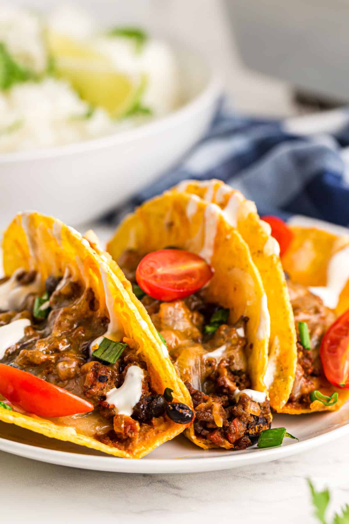 tacos on a white plate with ground beef and tomatoes 