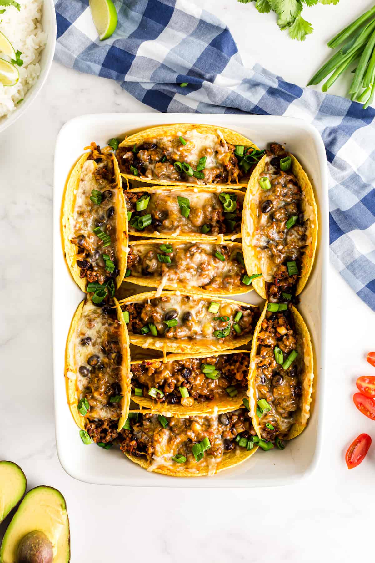 Tacos in a casserole dish with ground beef onion and cheese