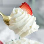 bite of whipped cream on a fork with a strawberry