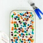 jello with different colored jello cubes with white gelatin mixture in a glass pan