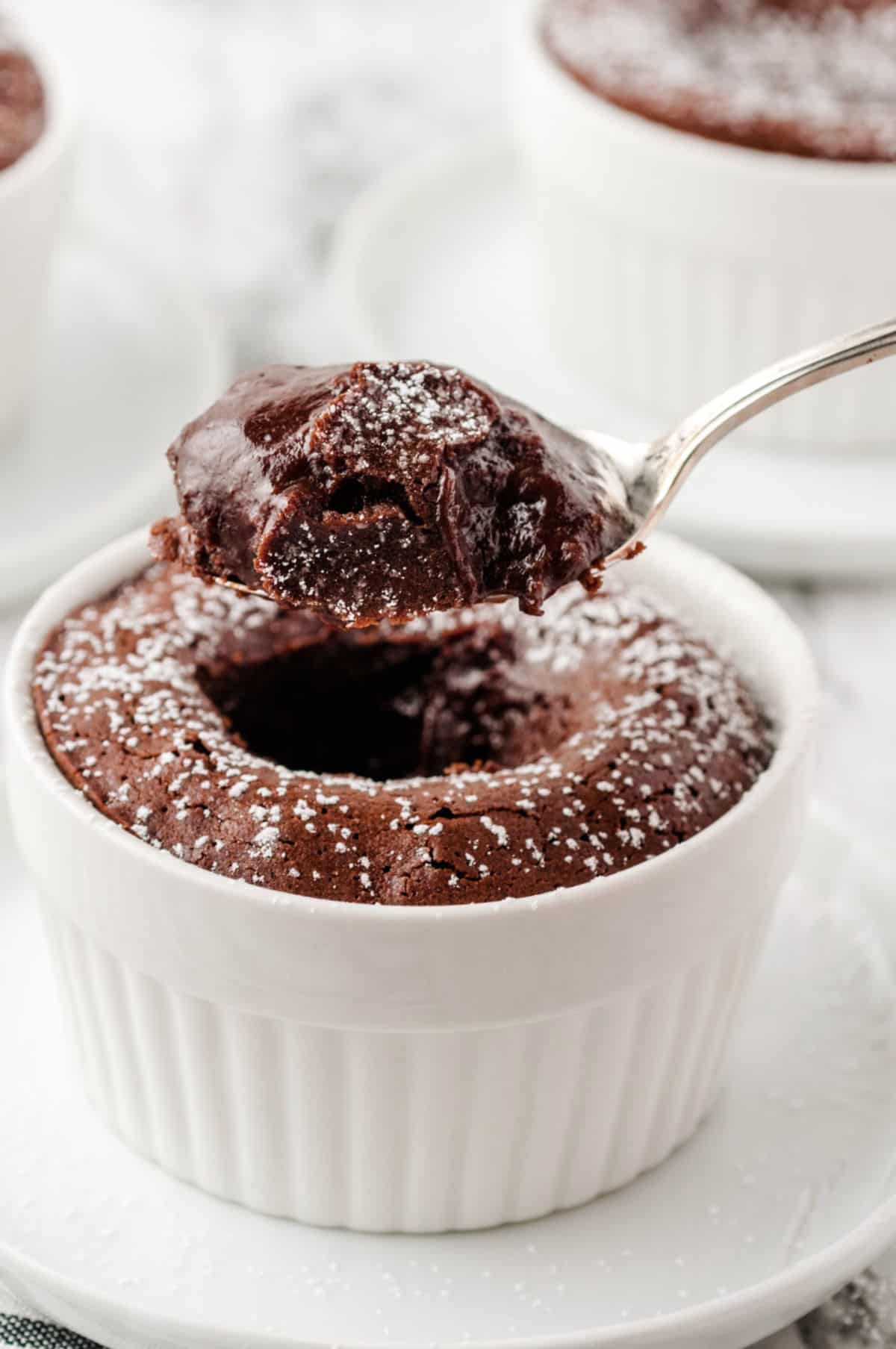 Chocolate Melting Cake in a white ramekin with a bite on a spoon