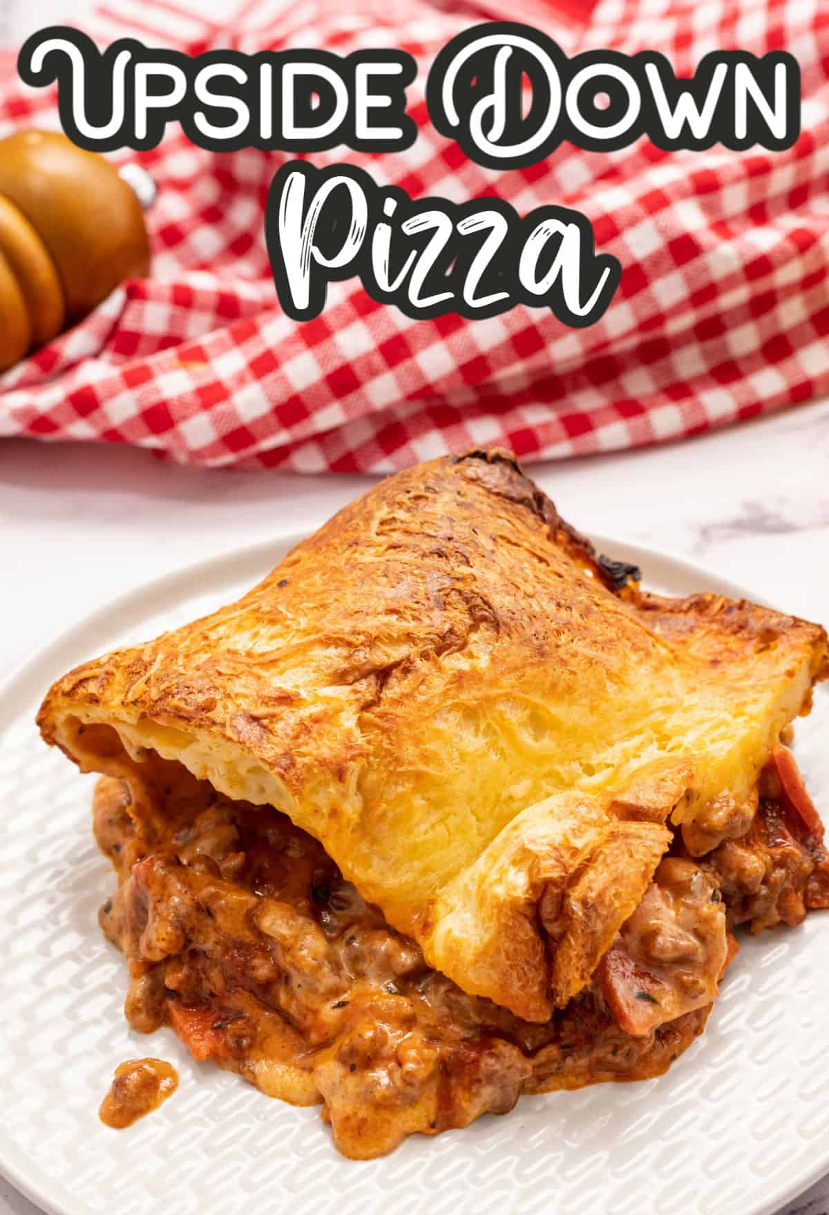 Upside down pizza on a white plate with red and white towel in background