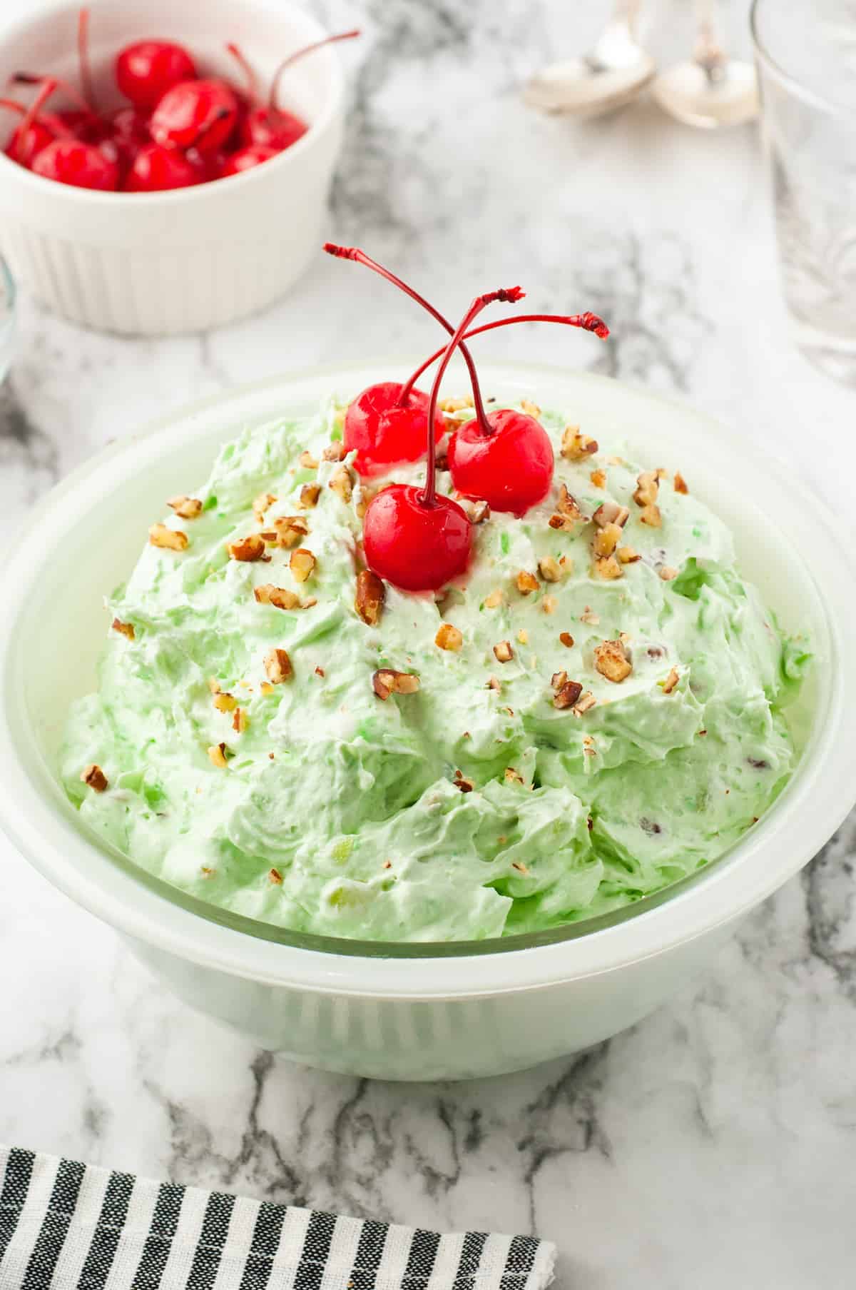 Watergate Salad with pecans and cherries in a white bowl