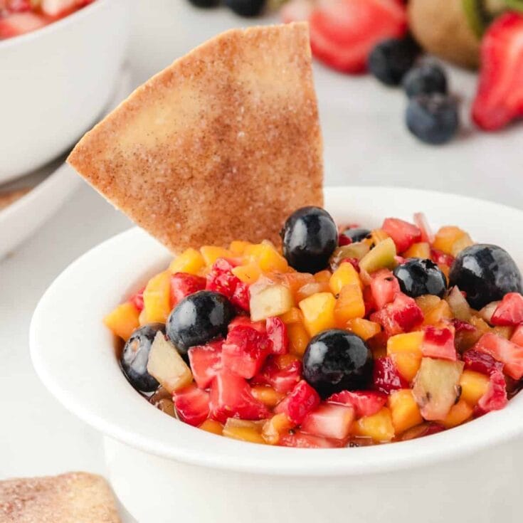 Fruit cut up in small pieces in a white bowl with a cinnamon chip