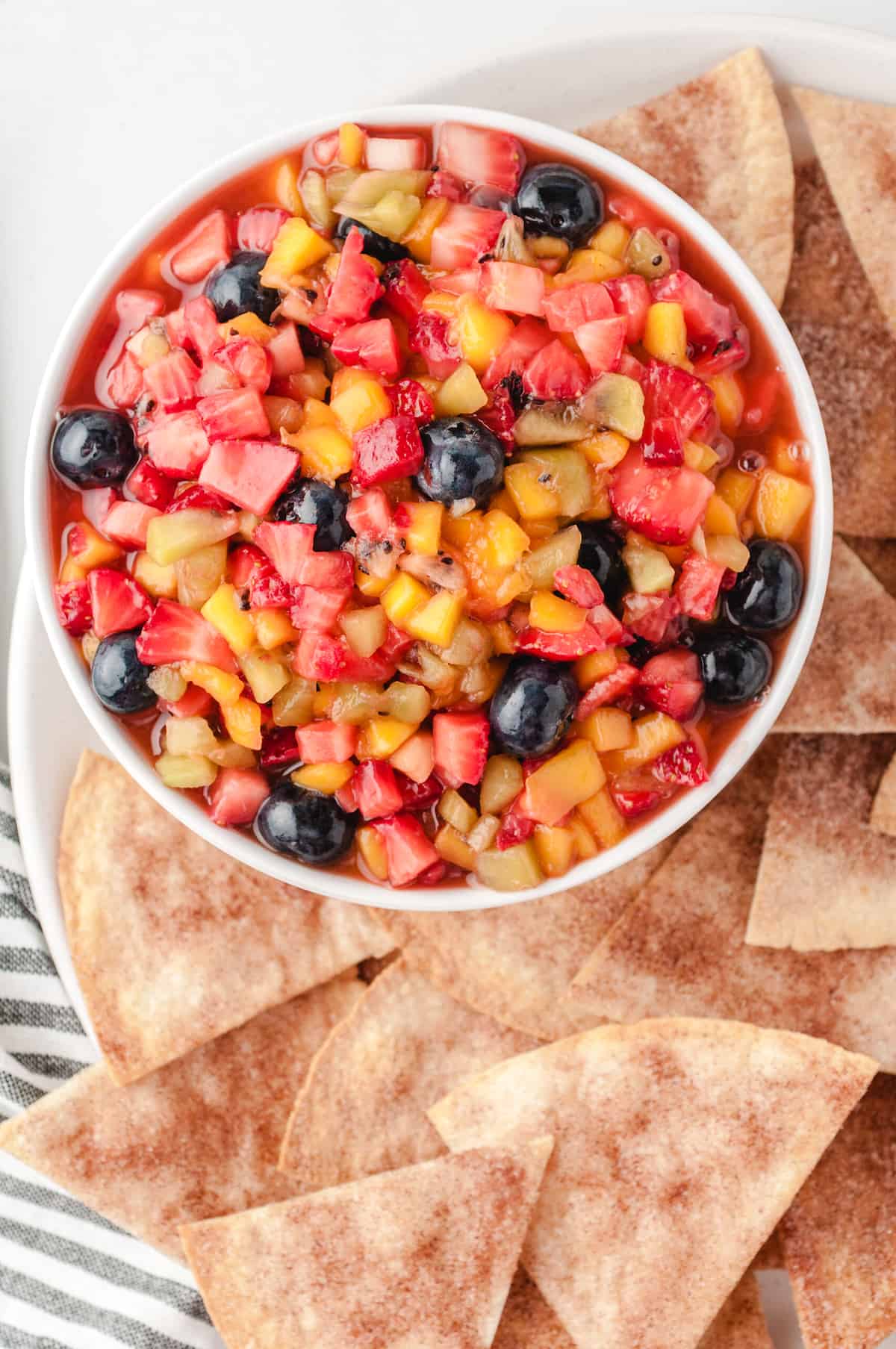 Fruit salsa in a white bowl with cinnamon chips