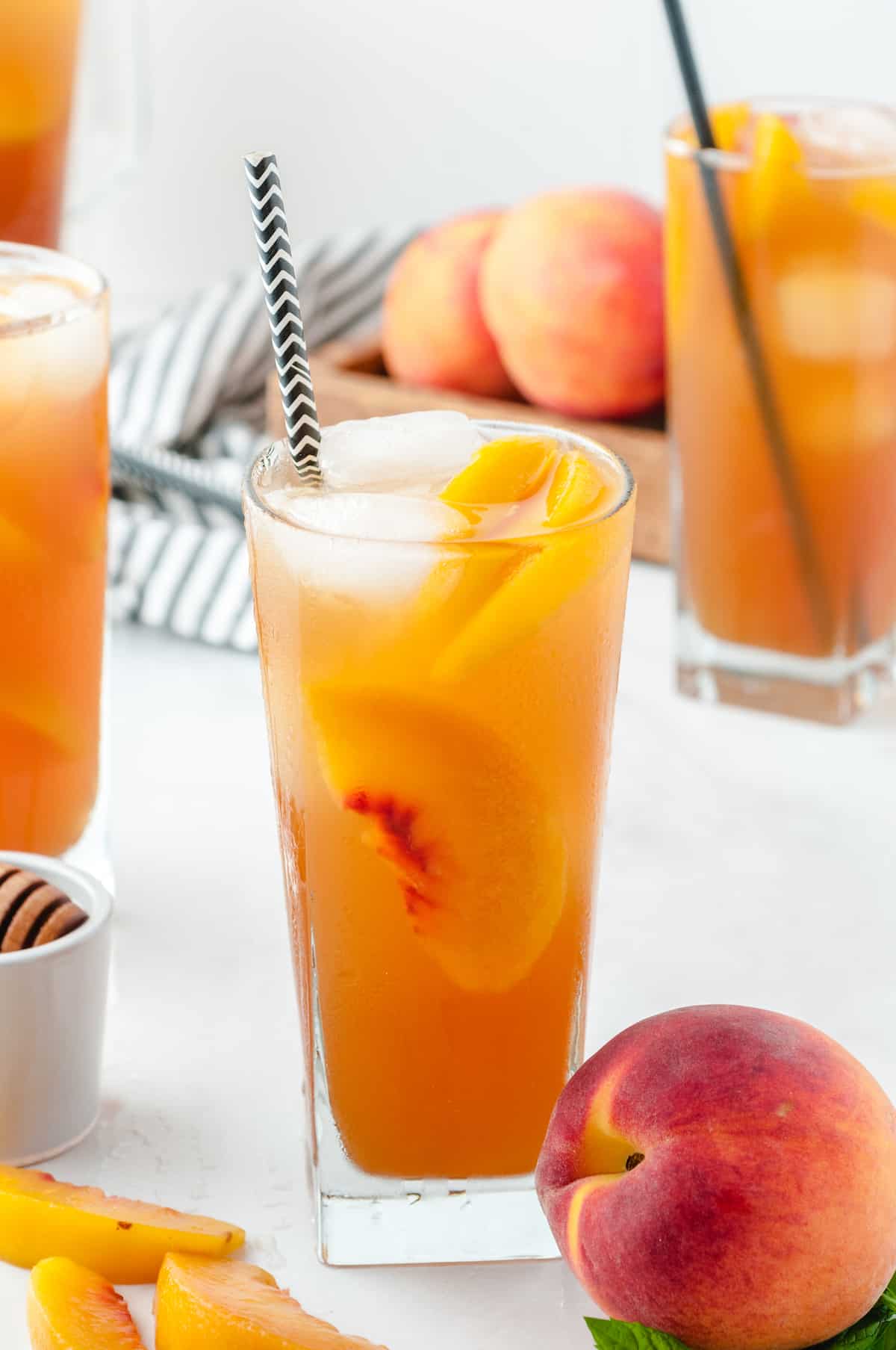 glass of peach ice tea with a peach next to it