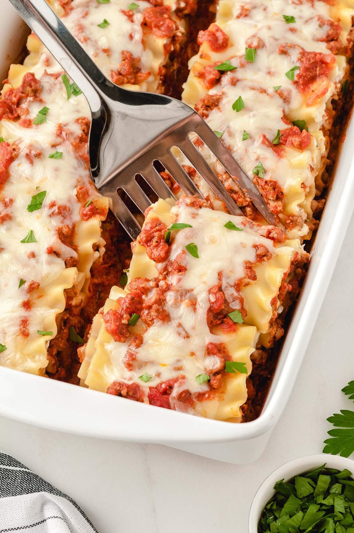 a plate of lasagna roll-ups inside casserole dish.