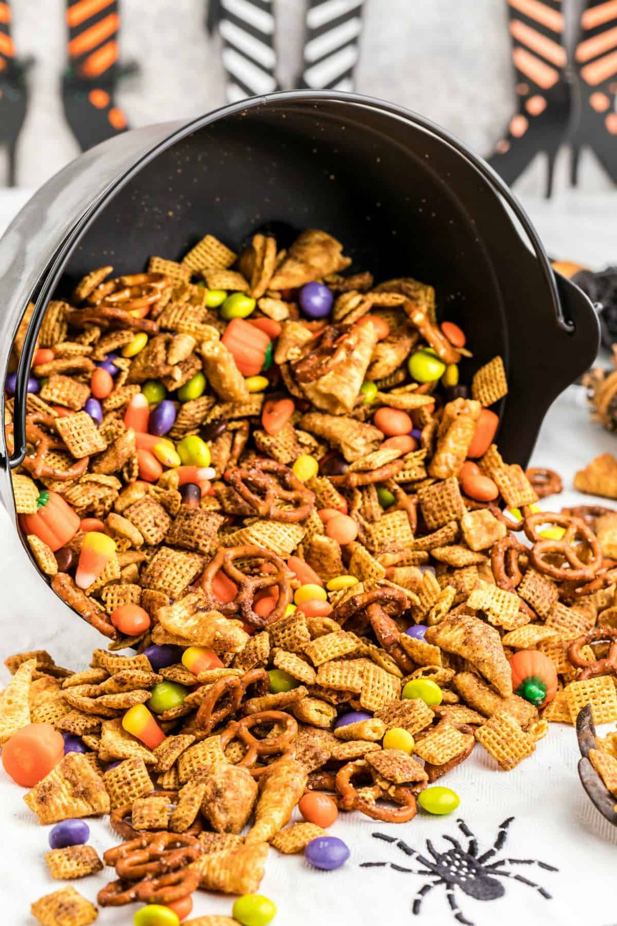 Halloween Chex Mix spilling out of a black cauldron