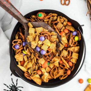 Halloween Chex Mix in a black bowl with a spider on the table cloth