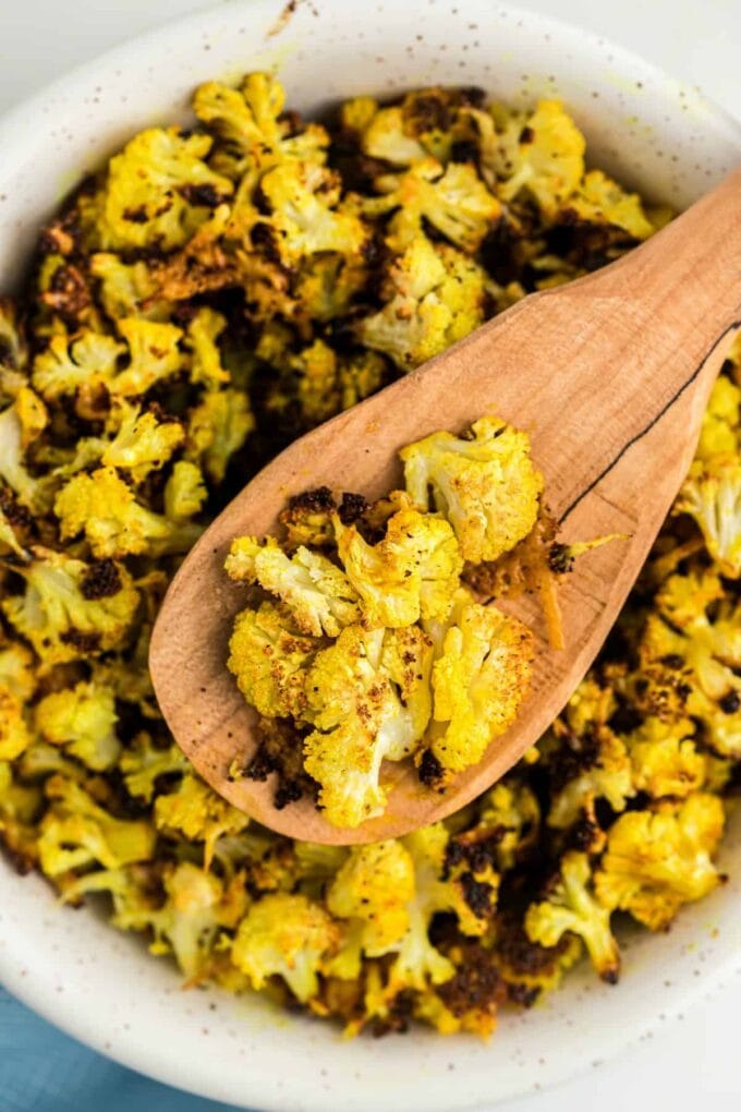 Roasted Cauliflower Popcorn in a white bowl on a wooden spoon