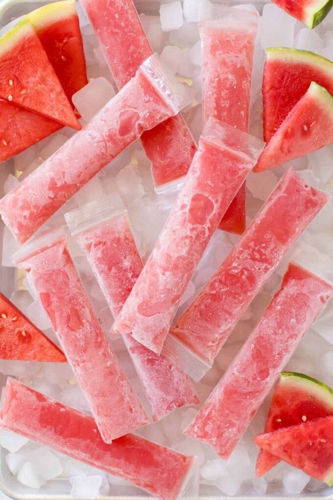 Watermelon Boozy Popsicles on ice with slices of watermelon