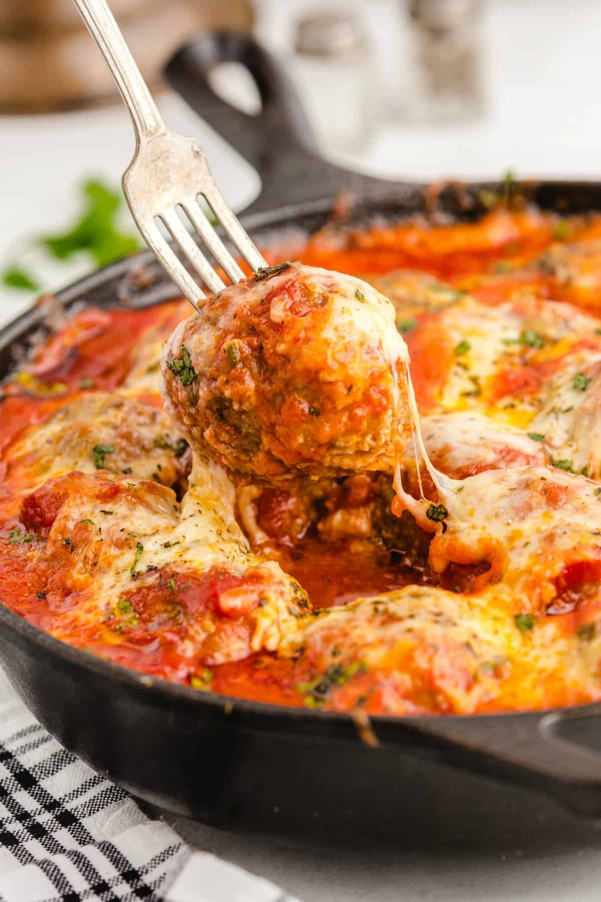 meatballs in red sauce with cheese in a cast iron skillet