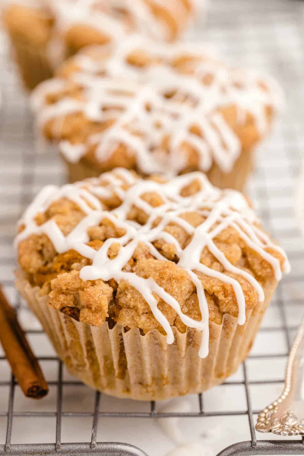 Pumpkin streusel muffin with white icing drizzle on a wire cooling rack.