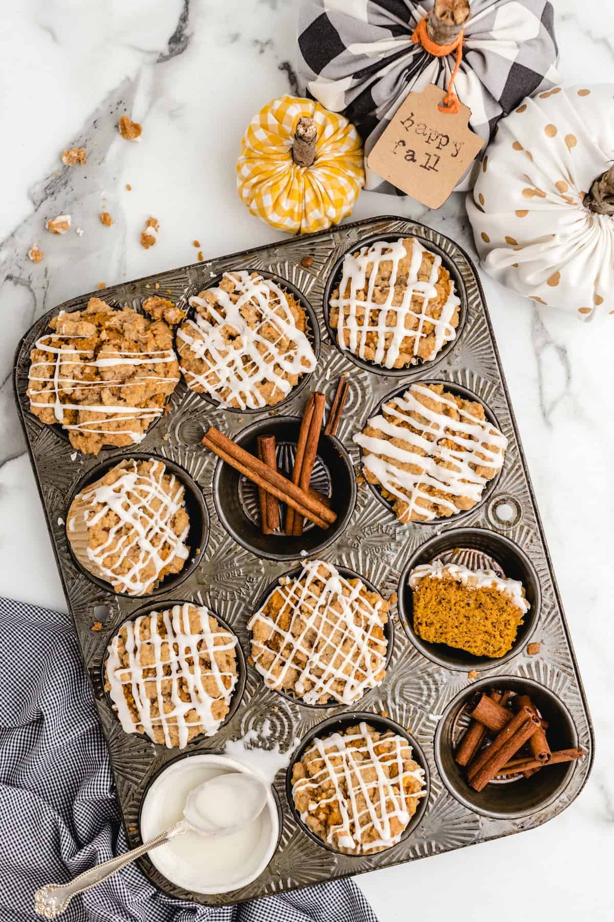 Freshly baked pumpkin streusel muffins with white drizzle in a vintage muffin pan.