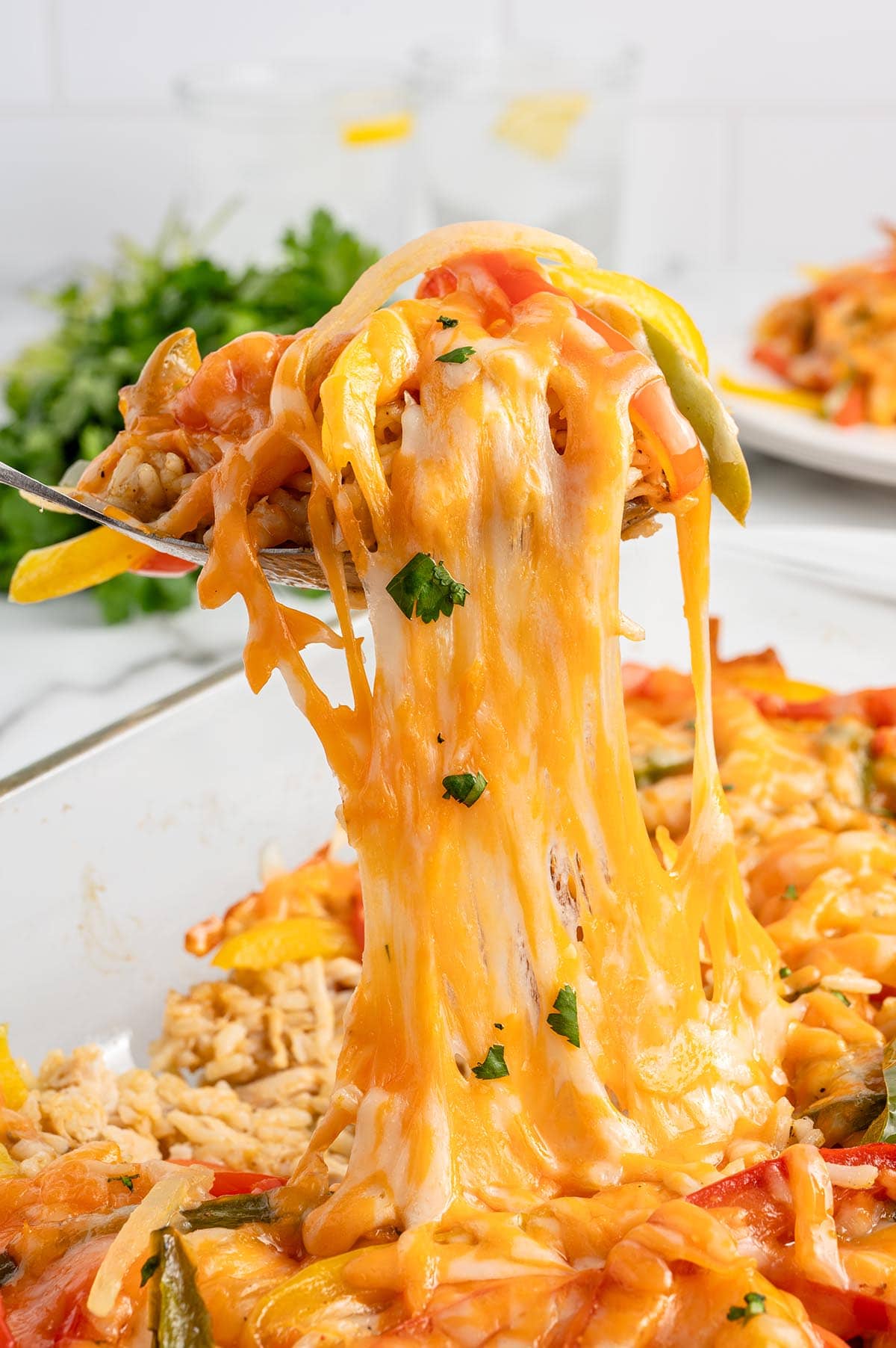 Cheesy chicken fajita casserole being lifted with a spoon, with melted cheese stretching.