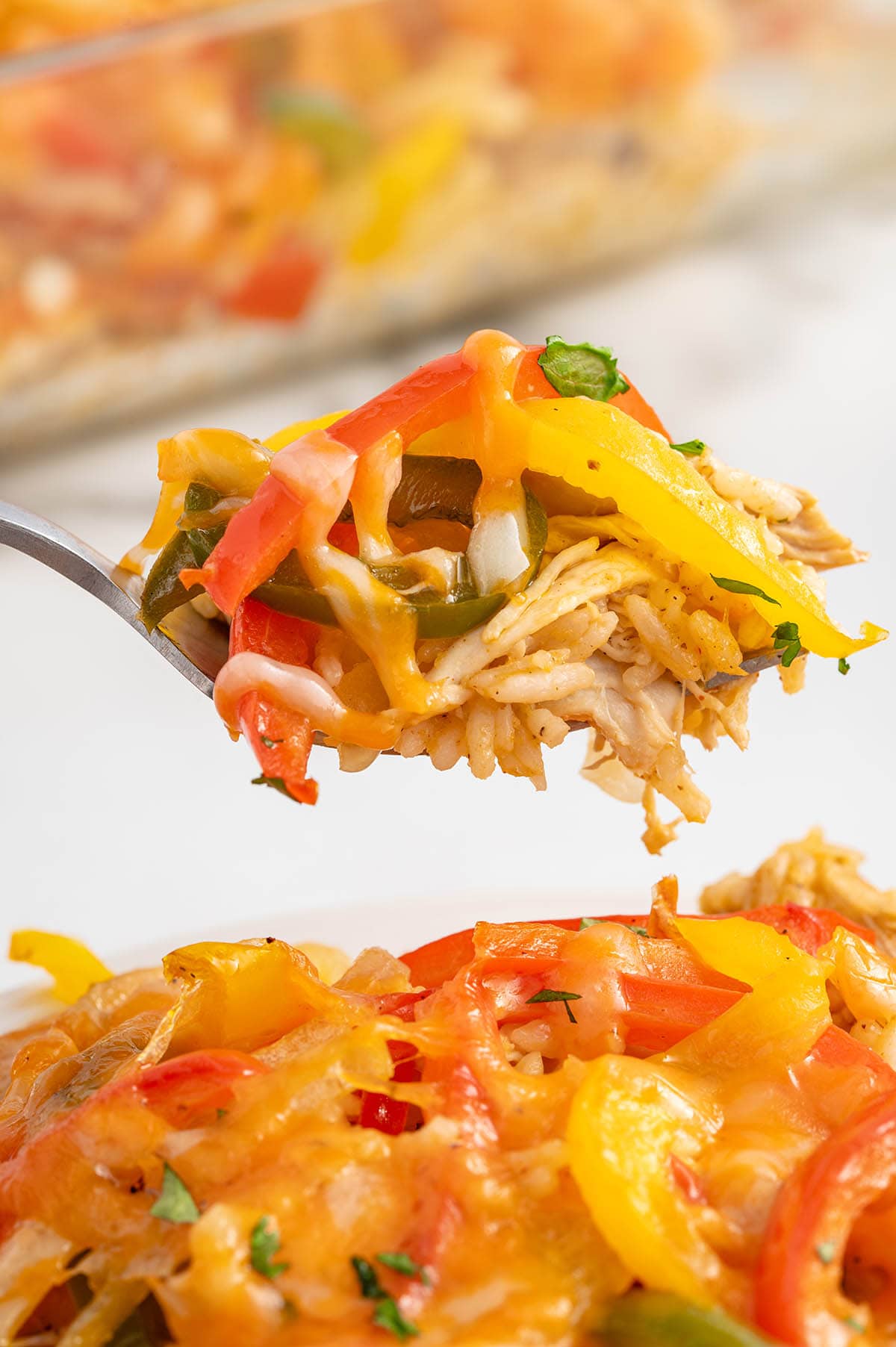 A spoonful of chicken fajita casserole with rice, bell peppers, and melted cheese.