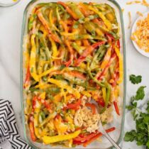 Chicken fajita casserole with shredded chicken, bell peppers, and melted cheese in a glass baking dish.