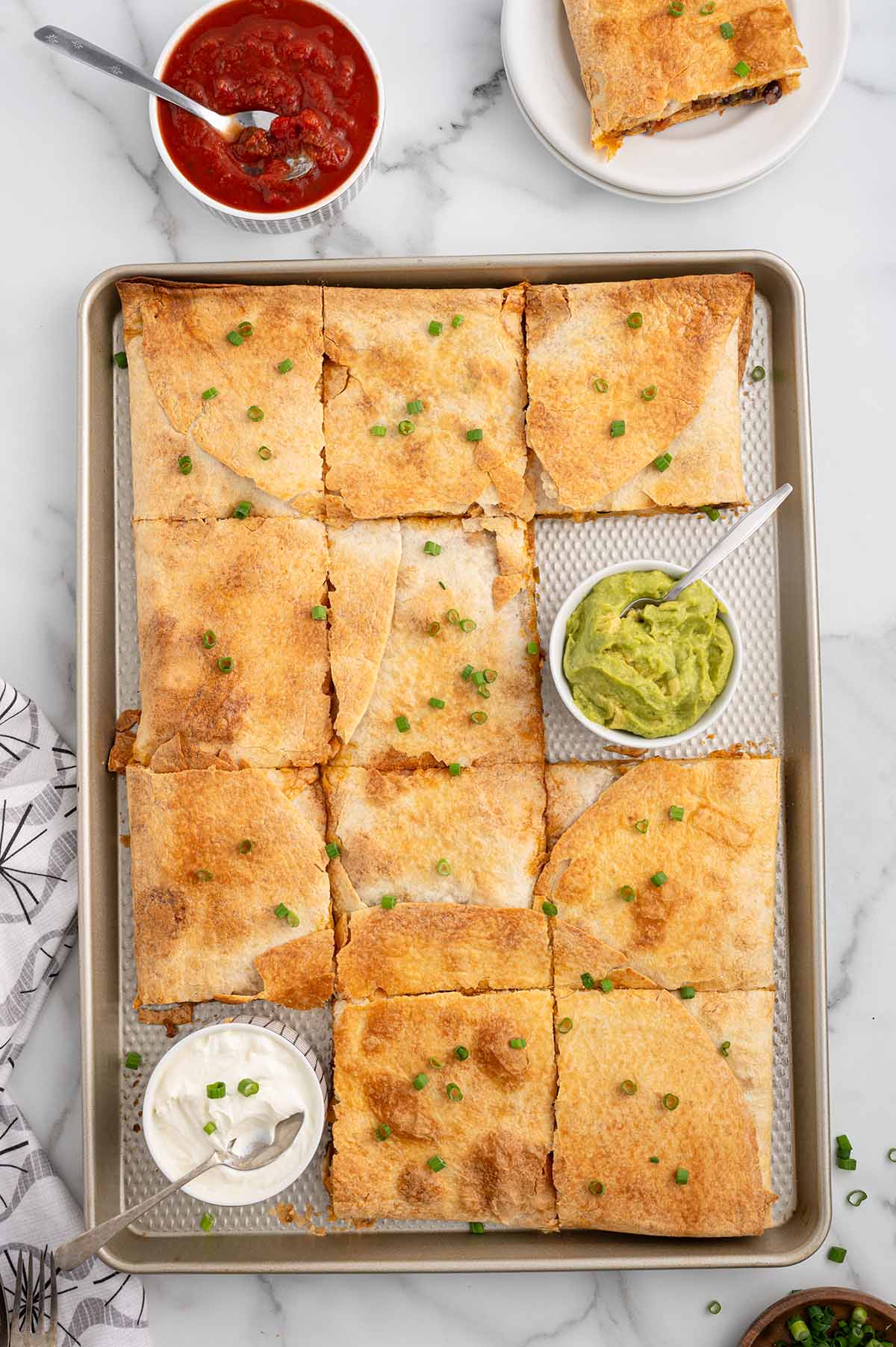 Sheet pan quesadillas with beef, cheese, and crispy tortillas, served with guacamole and sour cream.