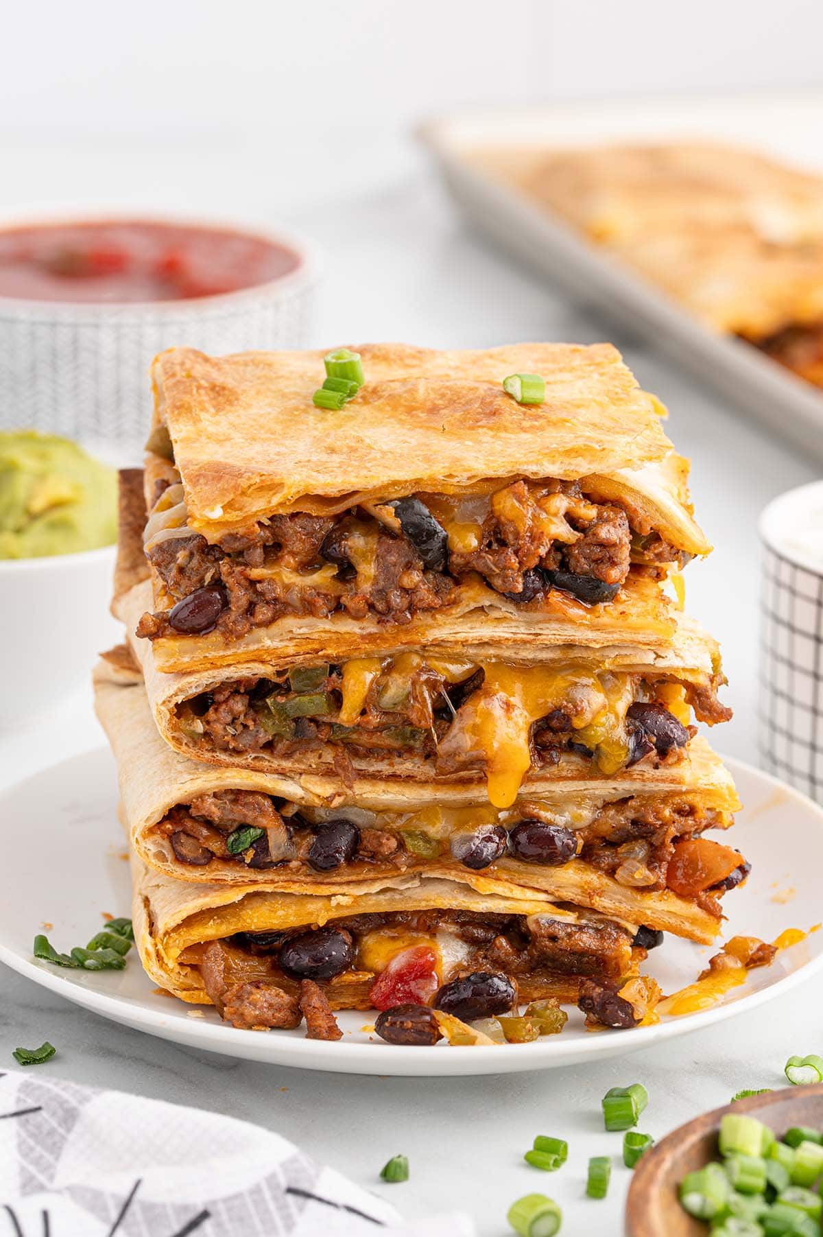 Stacked beef sheet pan quesadilla slices with melted cheese and black beans.