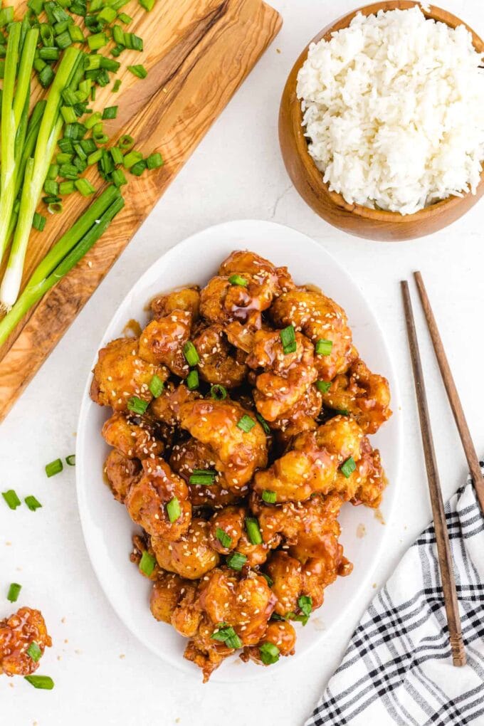 sesame cauliflower on a white place with a bowl of rice