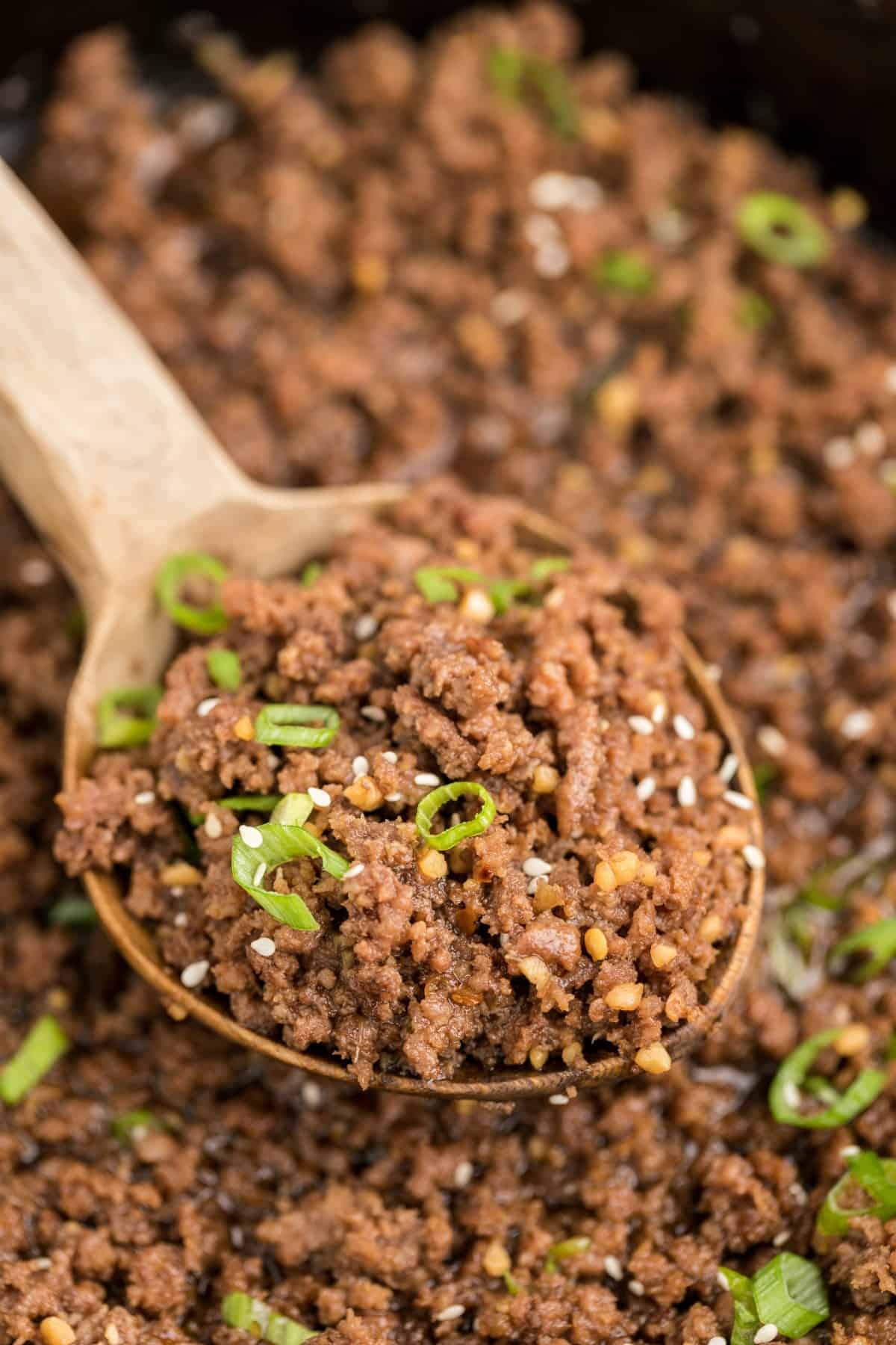 close up of ground beef on a wooden spoon.