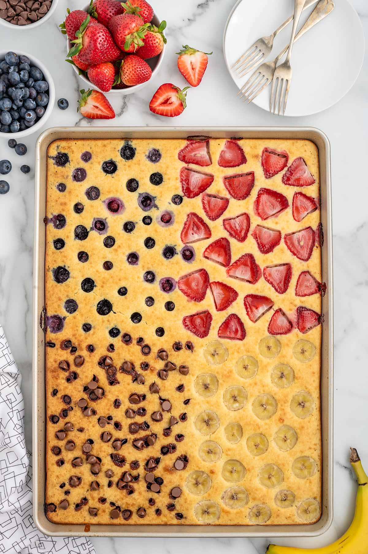 pancake in a sheet pan with multiple fruits as topping. 