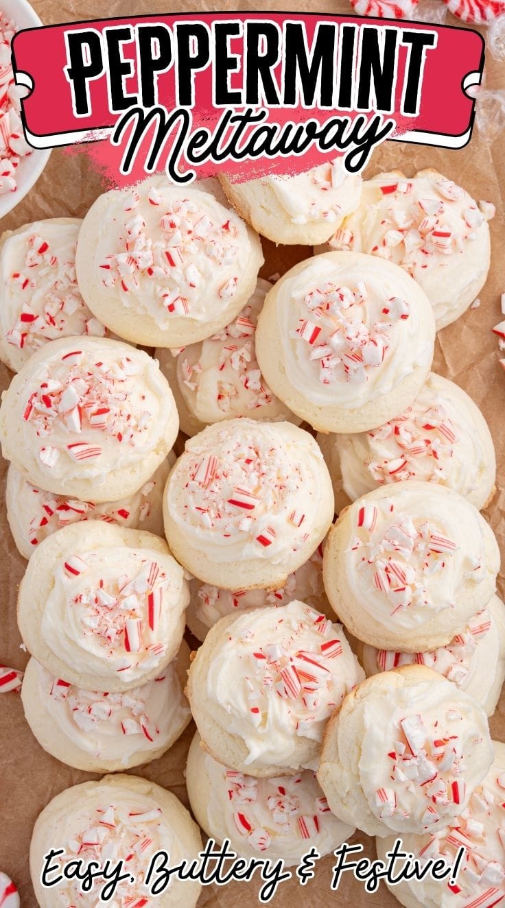 A bunch of peppermint meltaway cookies topped with crushed candies and frosting on a wooden board