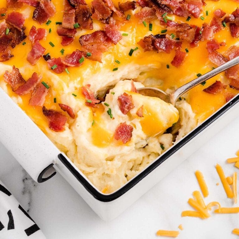 scooping mashed potato casserole in a casserole dish.