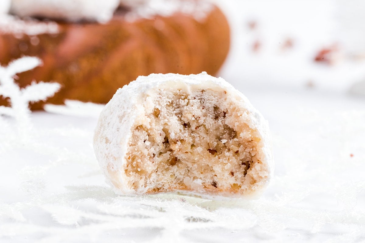 A snowball cookie with a bite out it showing the center