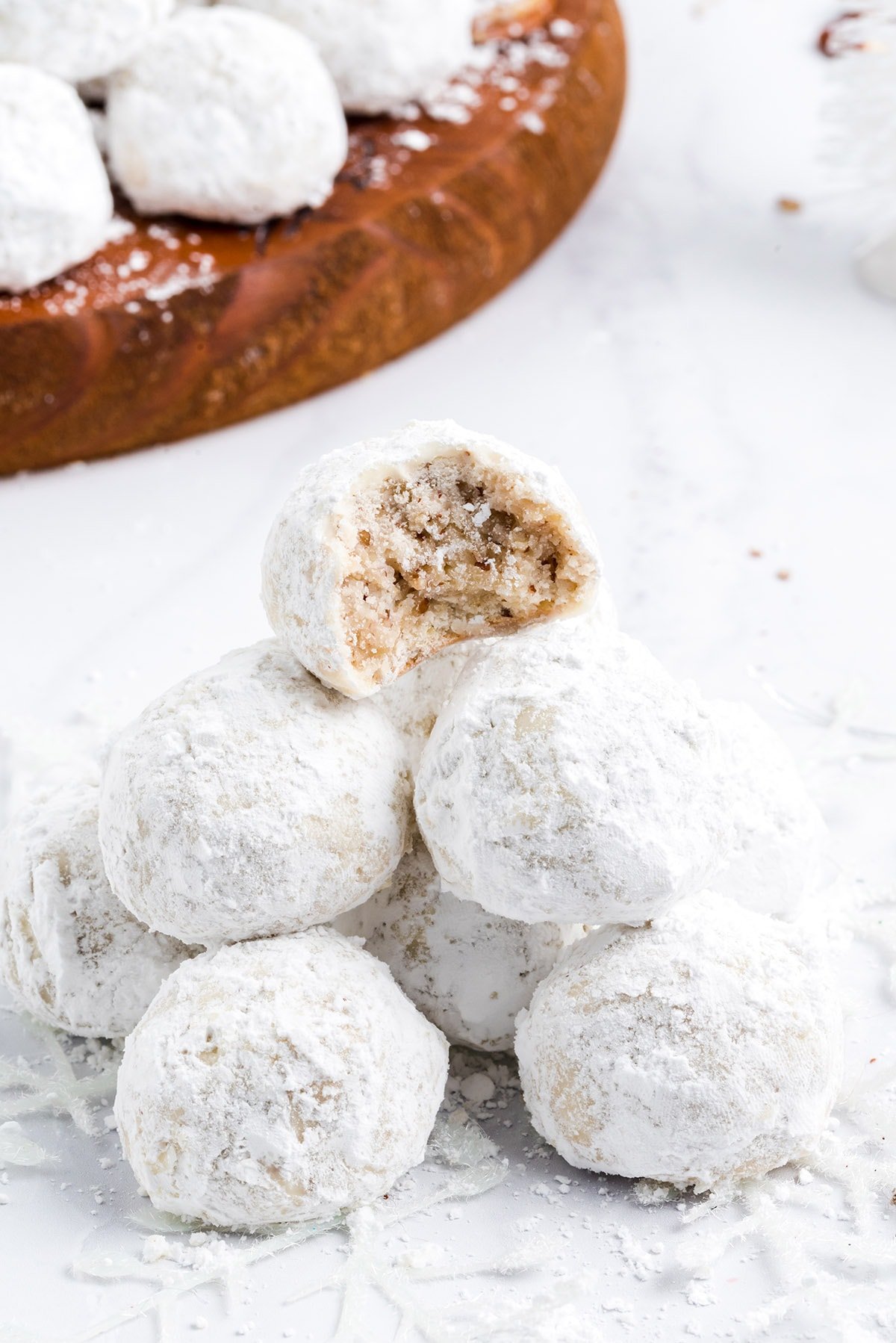 snowball cookies stacked with the top one having a bite out of it showing the middle.