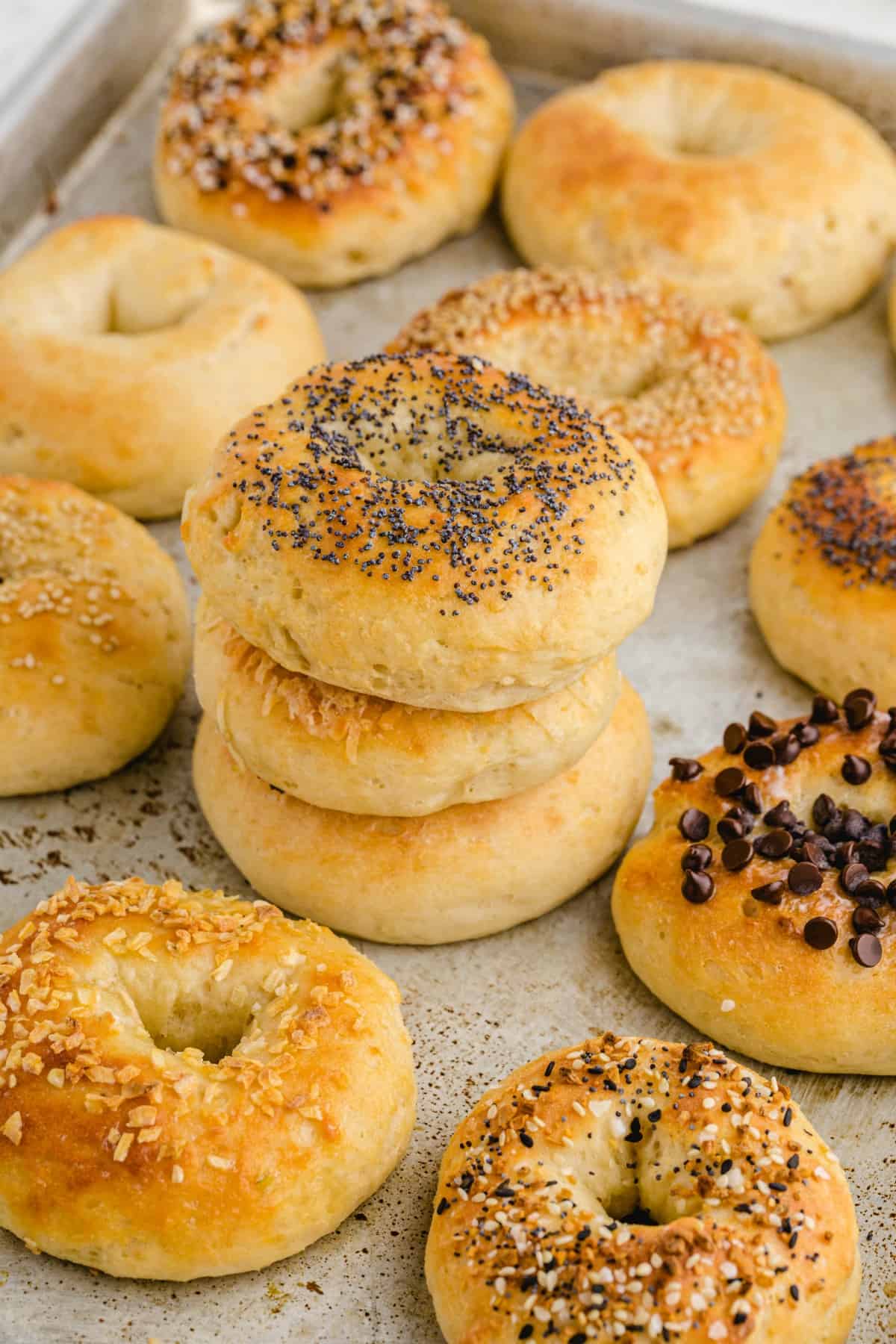 2 Ingredient Bagels stacked on top of baking sheet. 