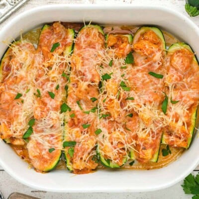 zucchini boats topped with shredded cheese and parshley.